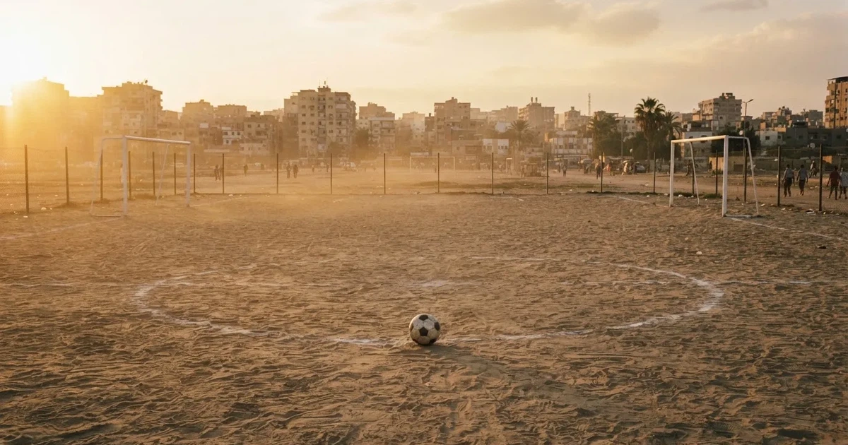 Ein sandiger Fußballplatz am Rand einer Stadt in warmem Abendlicht, Staub in der Luft und zwei Tore in der Ferne.